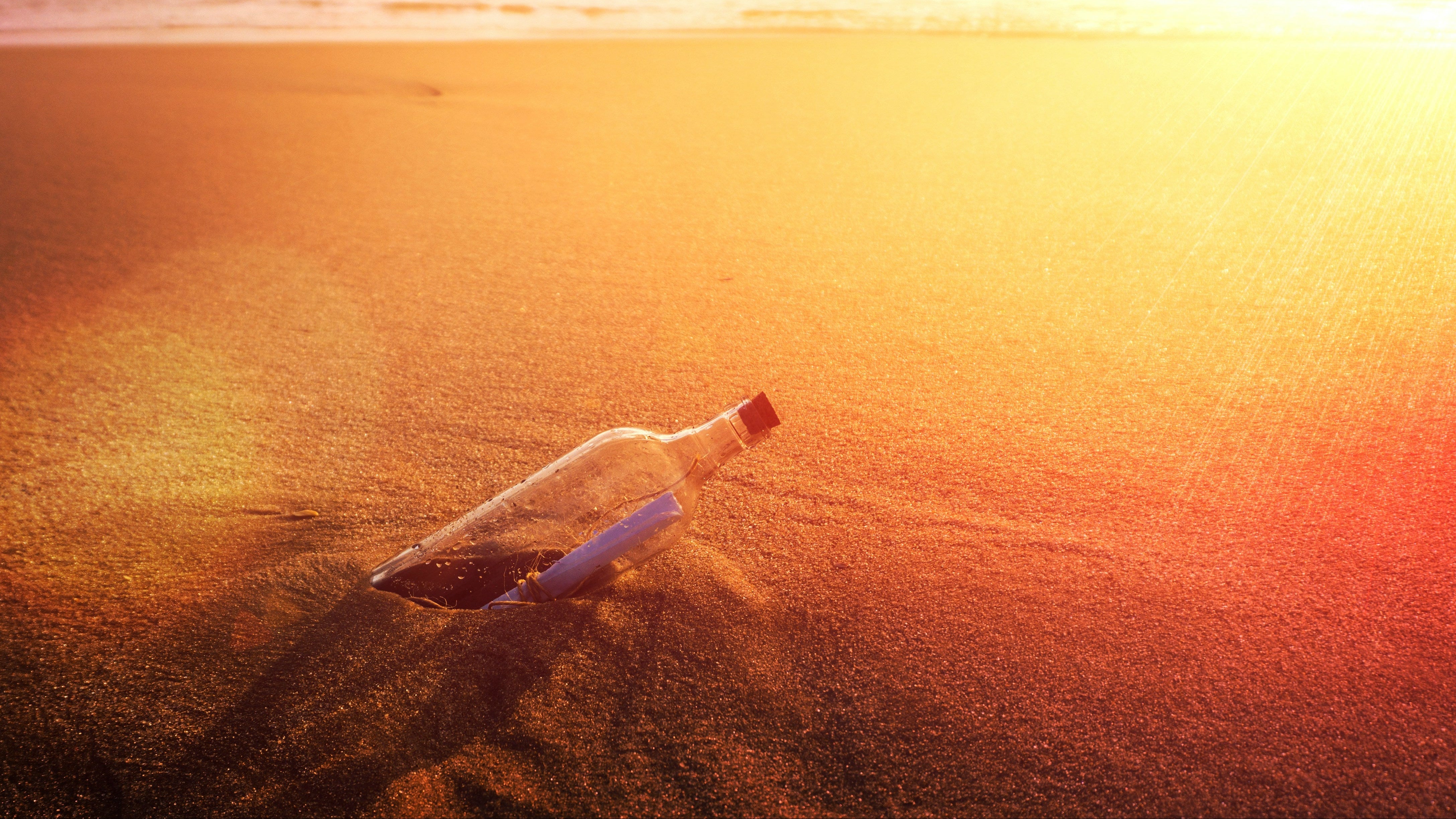 Glass bottle with a message inside on a beach at sunset